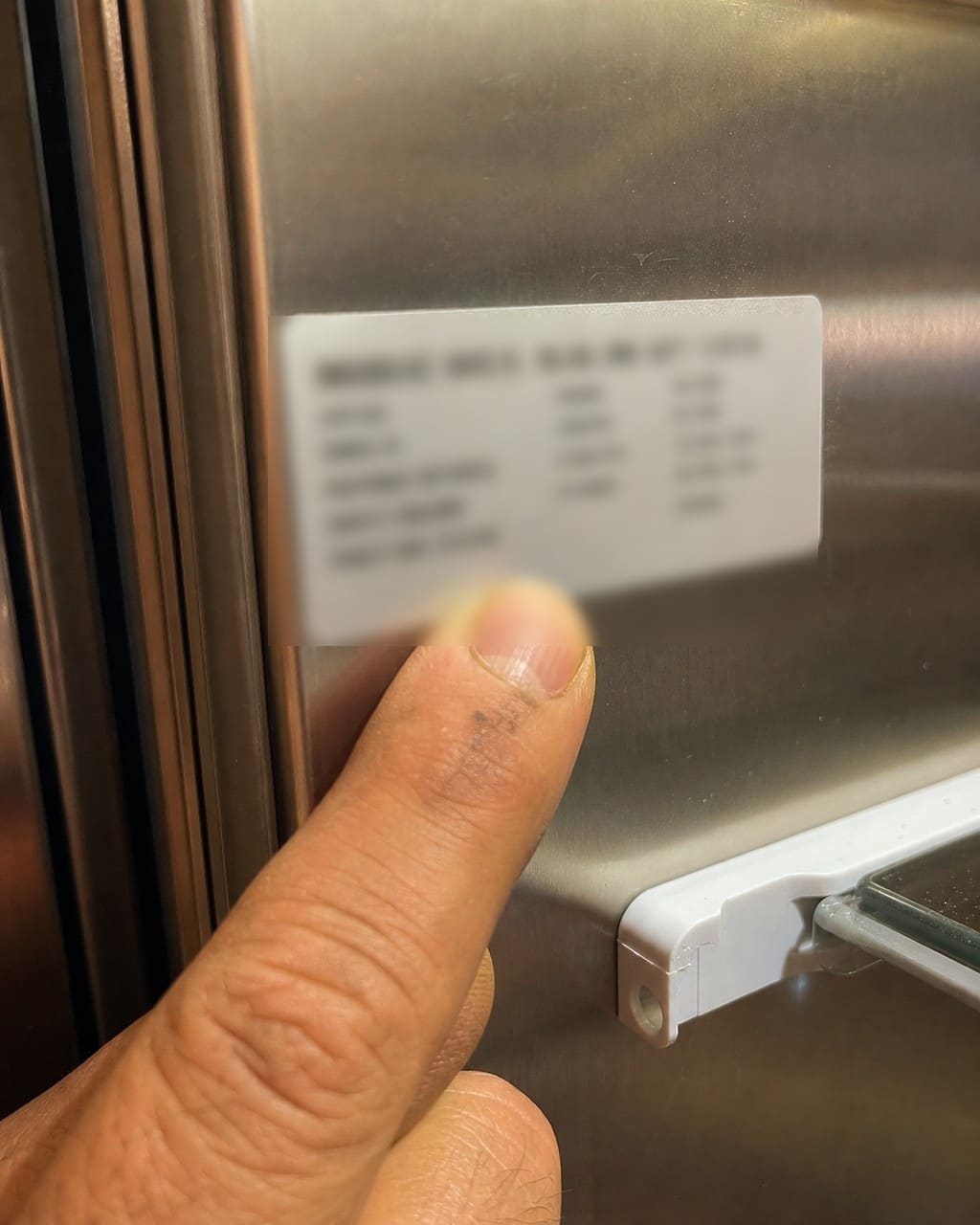 Close-up of a Sub-Zero model and serial number tag inside a refrigerator cabinet in Redwood City